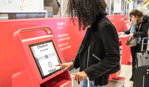 Woman using a self service airport kiosk with SuperNova magnified, black and white colour screen.